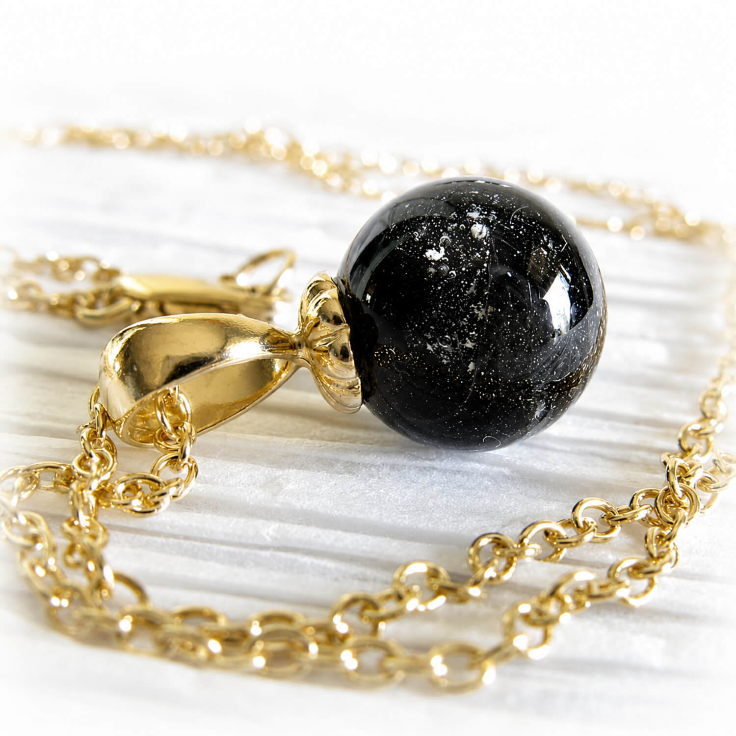 14k gold memorial necklace with a black glass marble on a white background