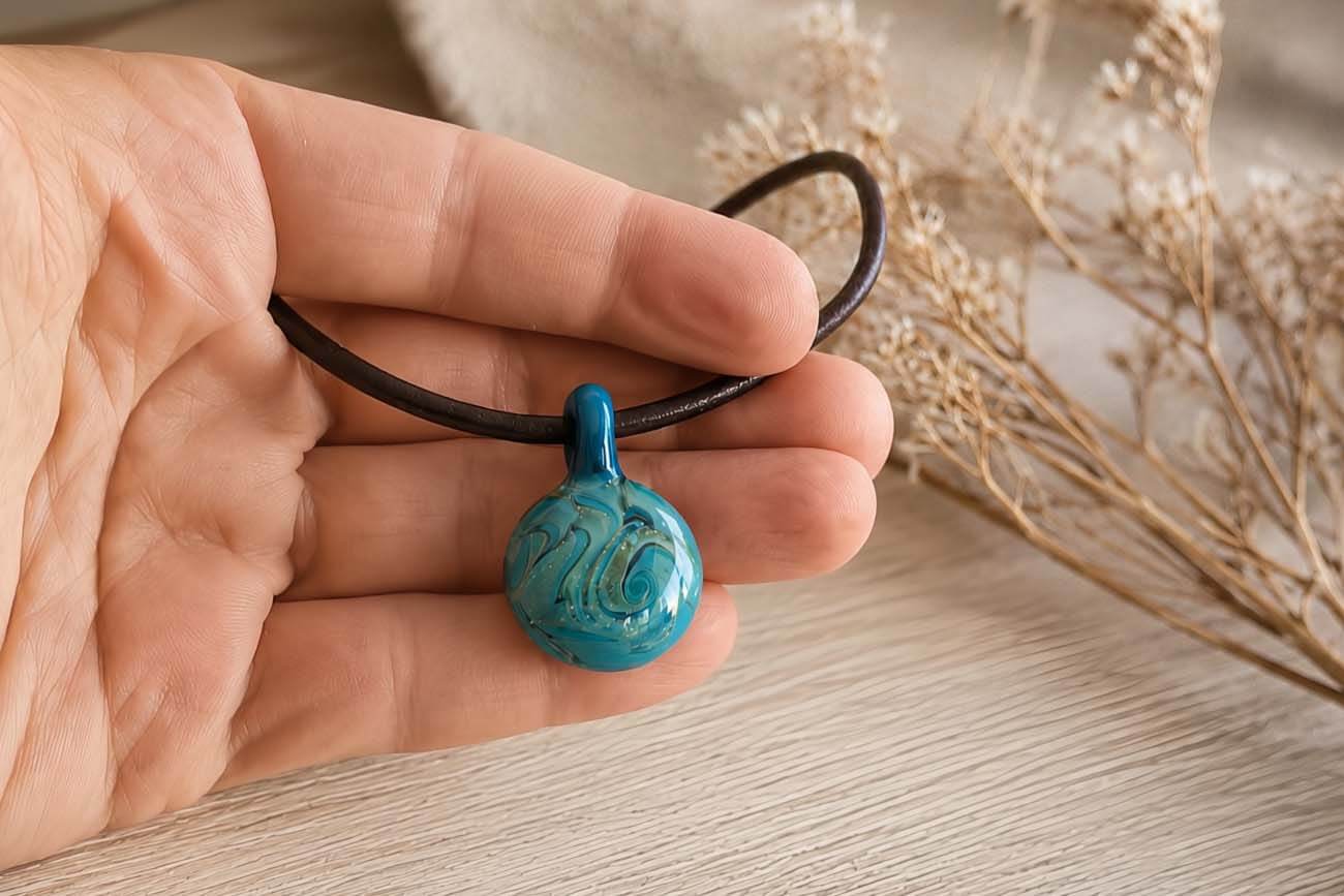Hand blown turquoise glass memorial pendant on a black leather necklace
