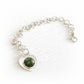 Hand crafted sterling silver charm bracelet with a heart-shaped focal charm featuring a green hand blown glass infused with cremation ashes
