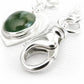 Close up of a high quality sterling silver lobster clasp on an artisan crafted charm bracelet with a green glass cremation cabochon 