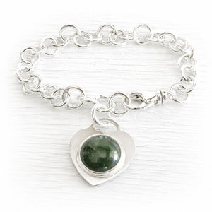 Sterling silver memorial charm bracelet with a heart-shaped charm featuring a green handcrafted memorial glass cabochon infused with ashes