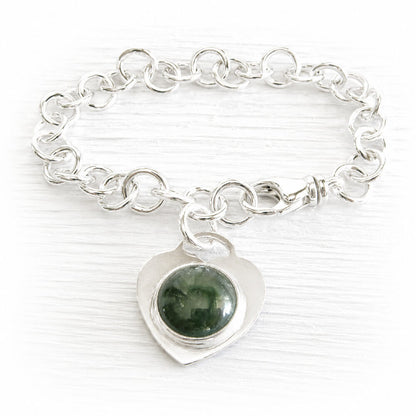 Sterling silver memorial charm bracelet with a heart-shaped charm featuring a green handcrafted memorial glass cabochon infused with ashes