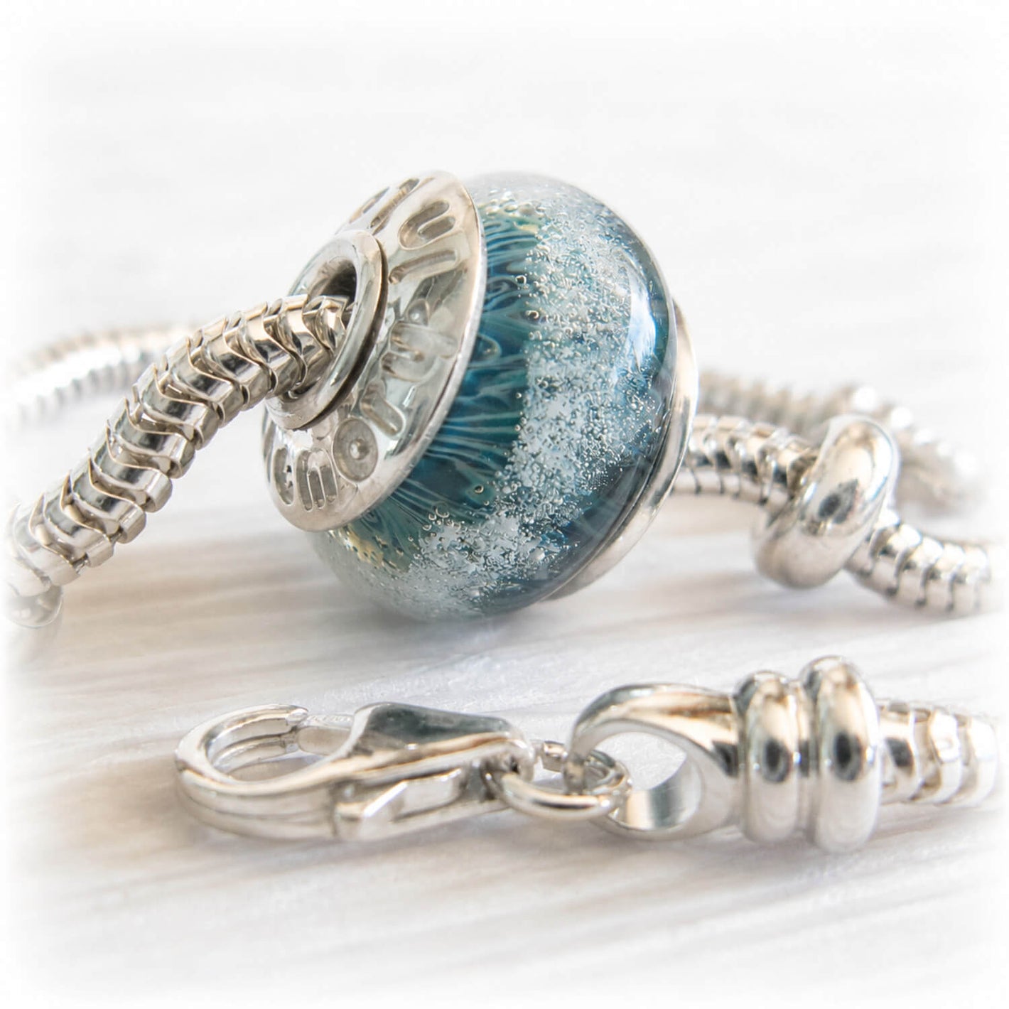 pet ashes suspended within a hand blown glass bead set with sterling silver bead caps engraved with personalized text