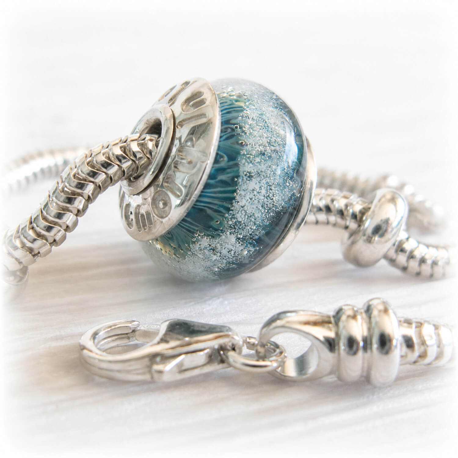 pet ashes suspended within a hand blown glass bead set with sterling silver bead caps engraved with personalized text