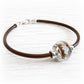 Brown leather bracelet together with a artisan crafted memorial bead containing ashes suspended within the glass