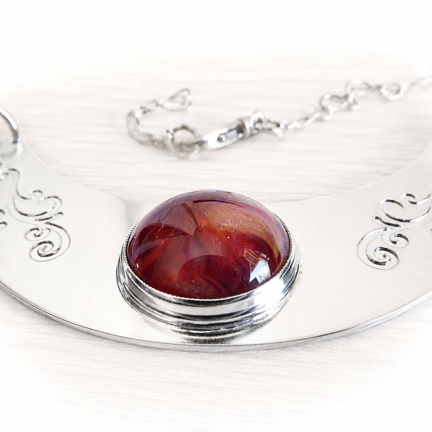Deep red hand blown glass dome with cremation ashes sealed within the glass set in a sterling silver memorial necklace