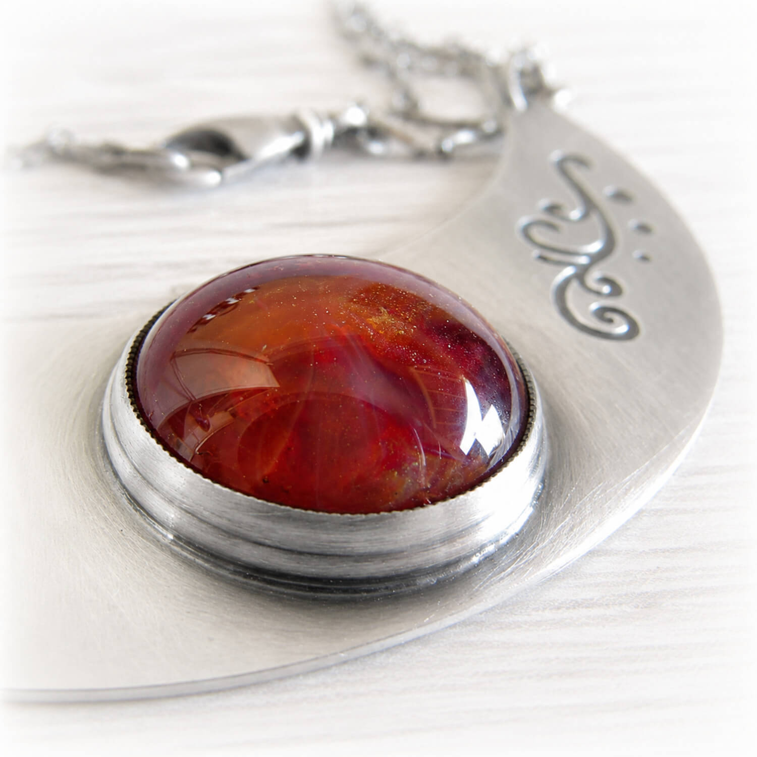 Ashes permanently sealed in hand blown glass in a sterling silver memorial pendant with engraving and an antique finish