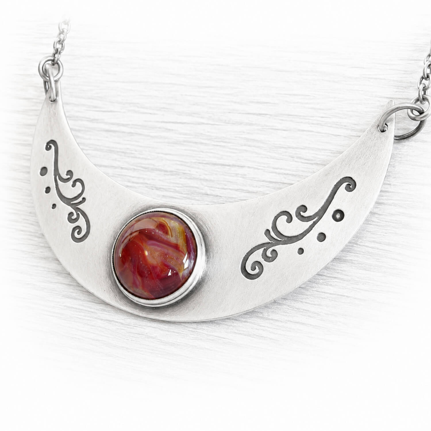 Antiqued finished sterling silver memorial necklace with a red hand blown glass gem stone swirled with pet ashes