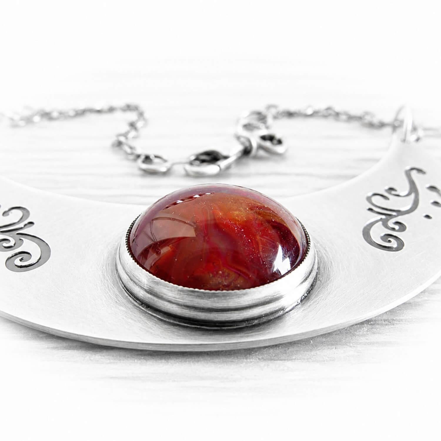 Red glass dome handcrafted with cremation ashes displayed on a sterling silver memorial pendant