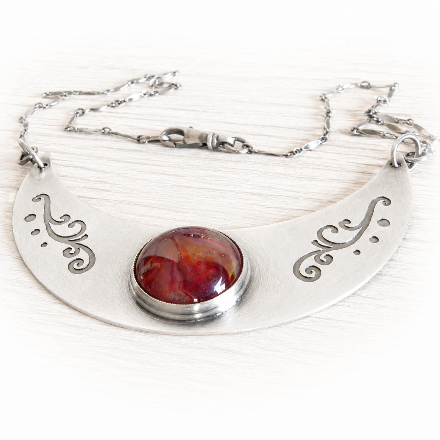 Sterling silver cremation necklace with a red hand blown glass cremation gem containing ashes sealed within the glass