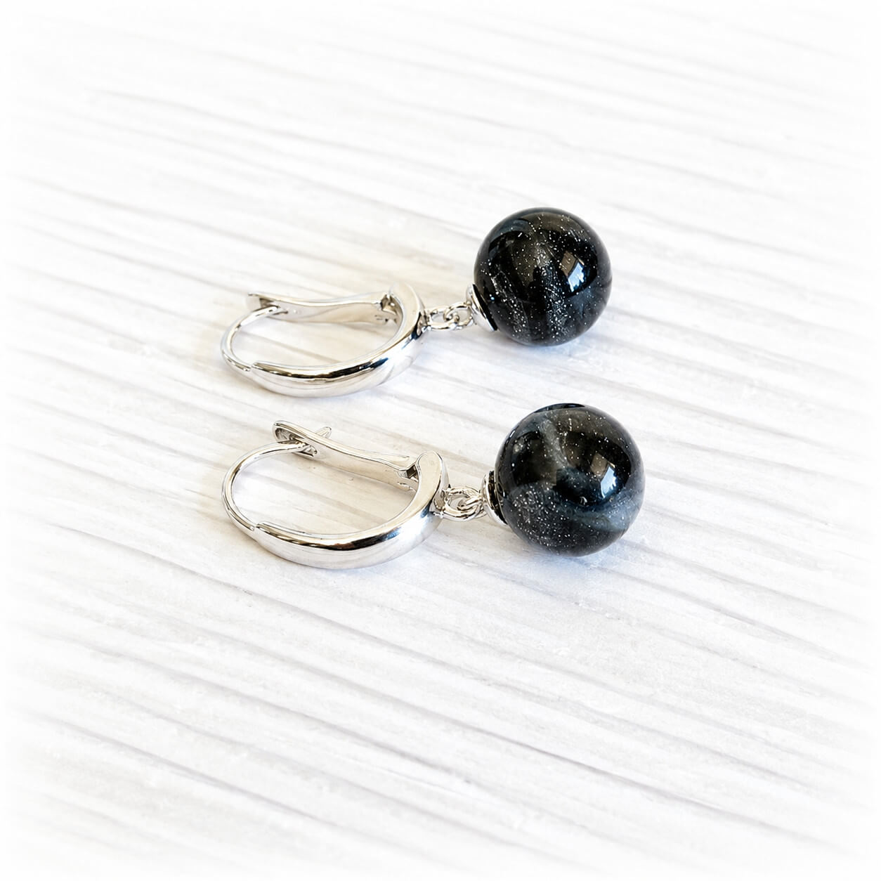 Black glass memorial marbles encasing cremation ashes on sterling silver leaver back earrings