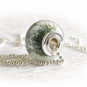 Handcrafted memorial glass cremation bead with ashes suspended within the glass on a sterling silver bead chain