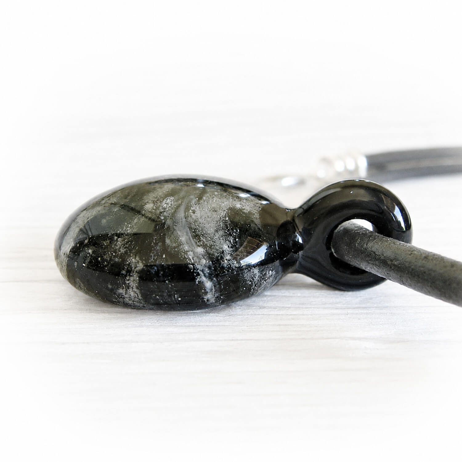 Black glass mixed with swirls of white cremation ashes made into a memorial glass pendant keepsake 