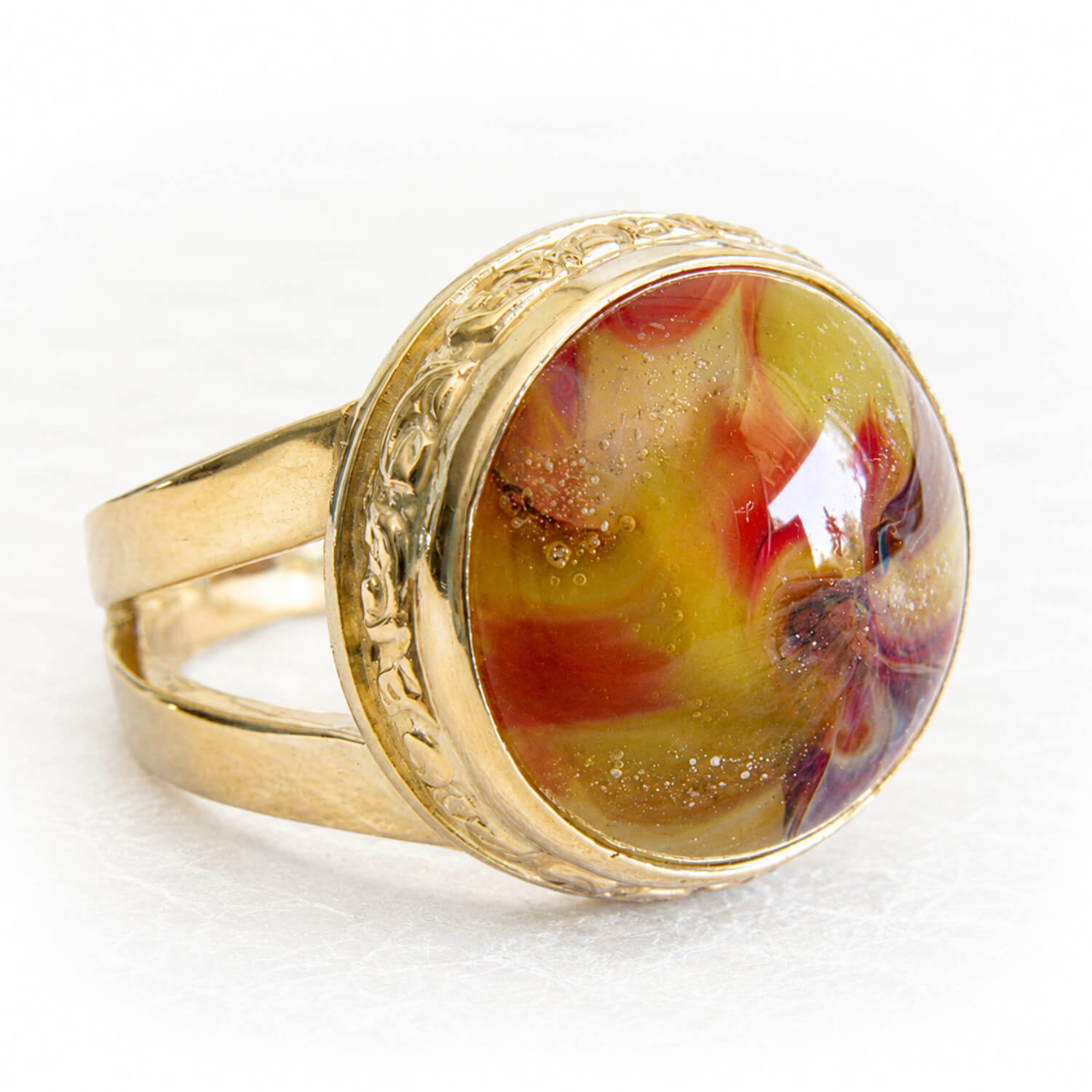 Gold memorial ring featuring a colorful circular glass dome with cremation ashes sealed within the glass