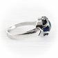 A silver ring with blue cremation glass cabochon, shown on a light gray background.