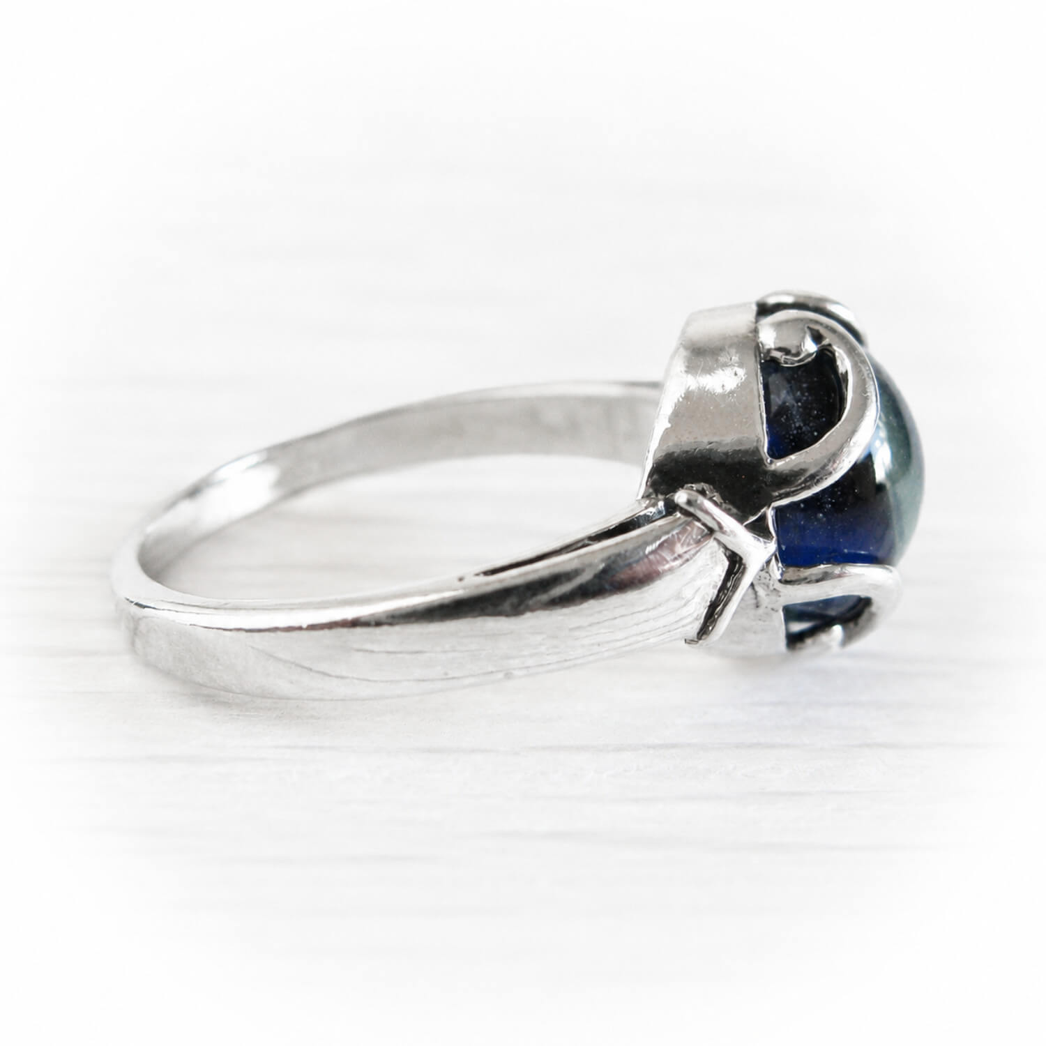 A silver ring with blue cremation glass cabochon, shown on a light gray background.