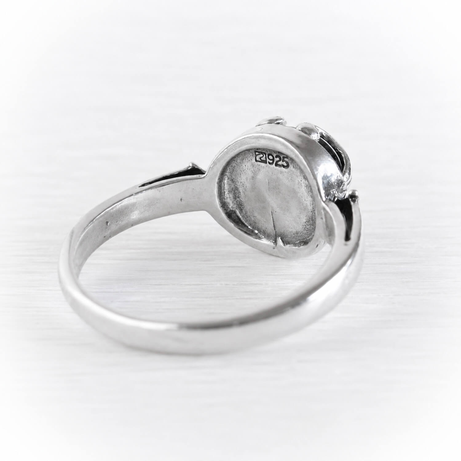 A silver ring shown from the back, featuring a polished band and a round bezel setting. The inside of the ring is stamped with 'S925', indicating sterling silver.