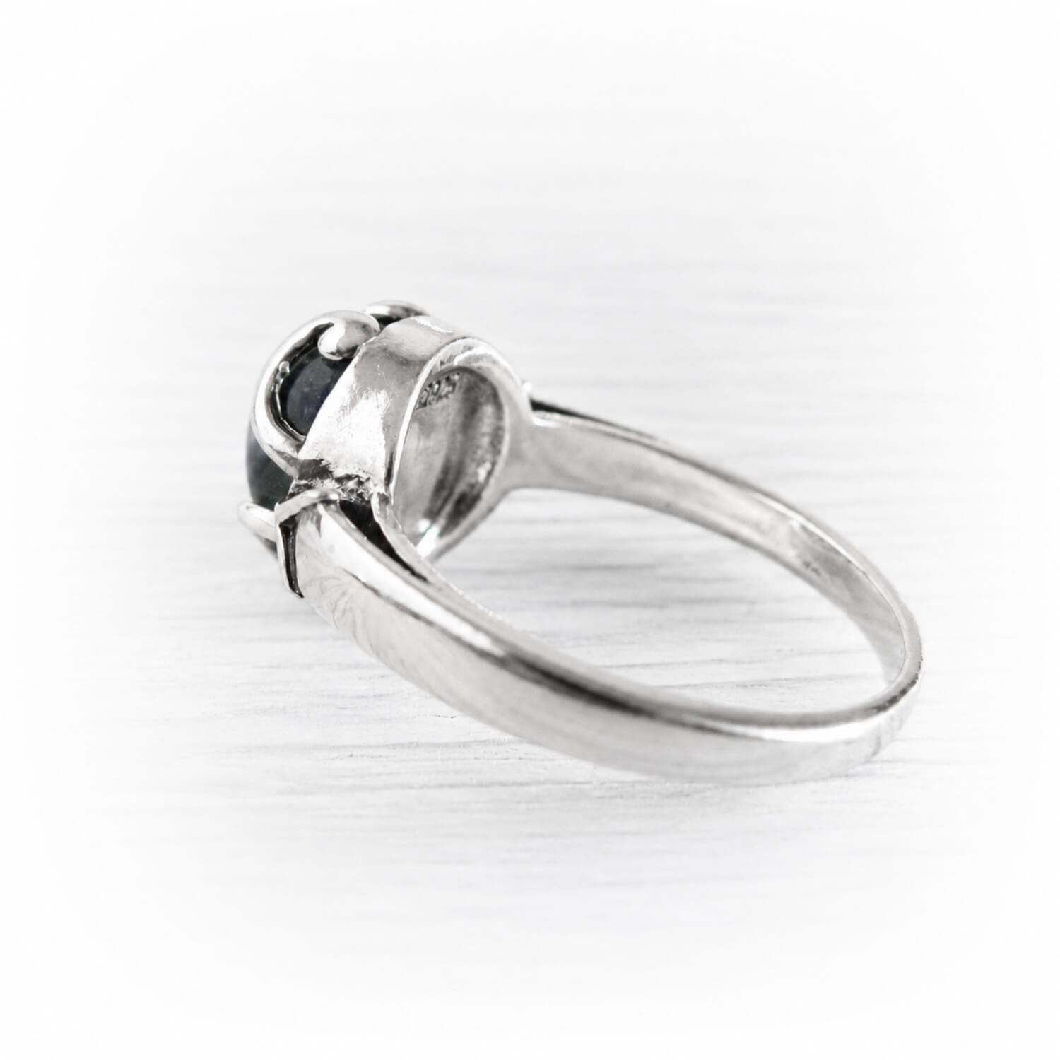 A silver ring with a cremation glass cabochon in a prong setting, shown on a light gray background.