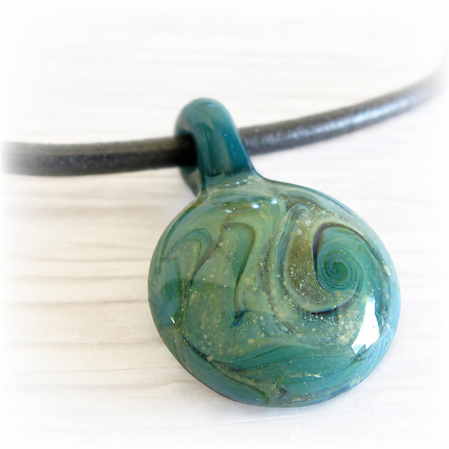 Hand blown glass memorial pendant handcrafted with cremation ashes on a black leather chord