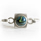Cremation ashes encased blue and green hand blown glass set in a sterling silver bangle bracelet 
