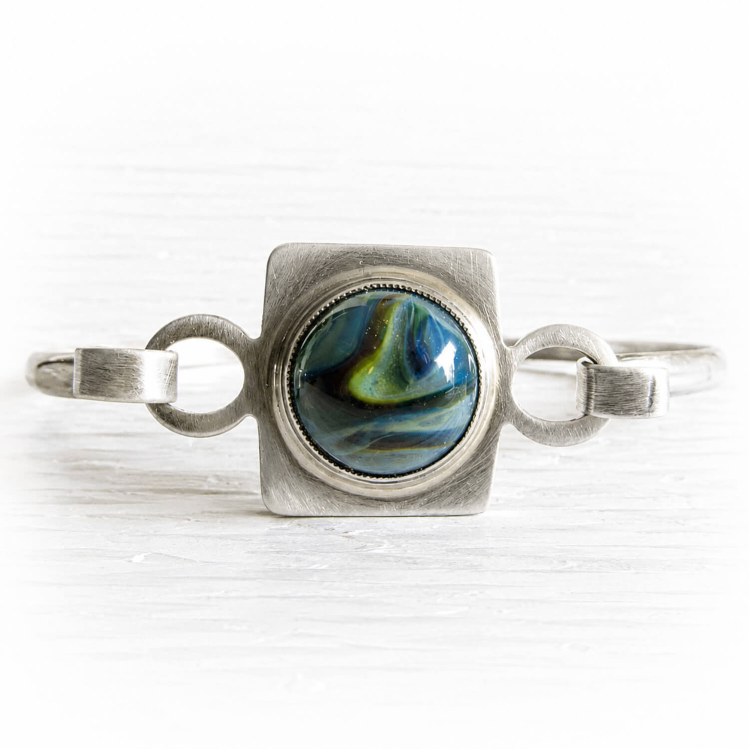 Cremation ashes encased blue and green hand blown glass set in a sterling silver bangle bracelet 