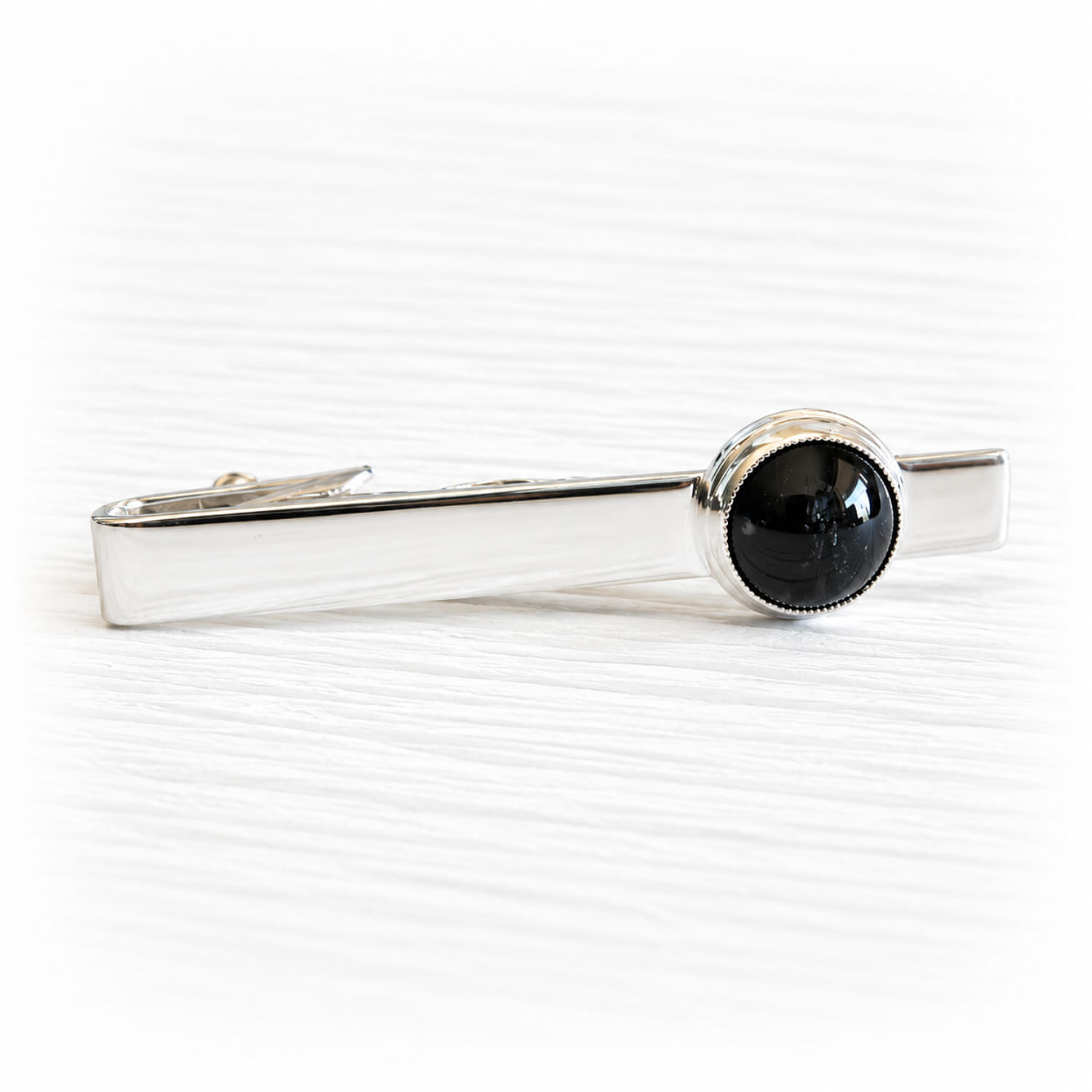 Black glass memorial gem hand blown with cremation ashes sealed within the glass set on a sterling silver tie bar