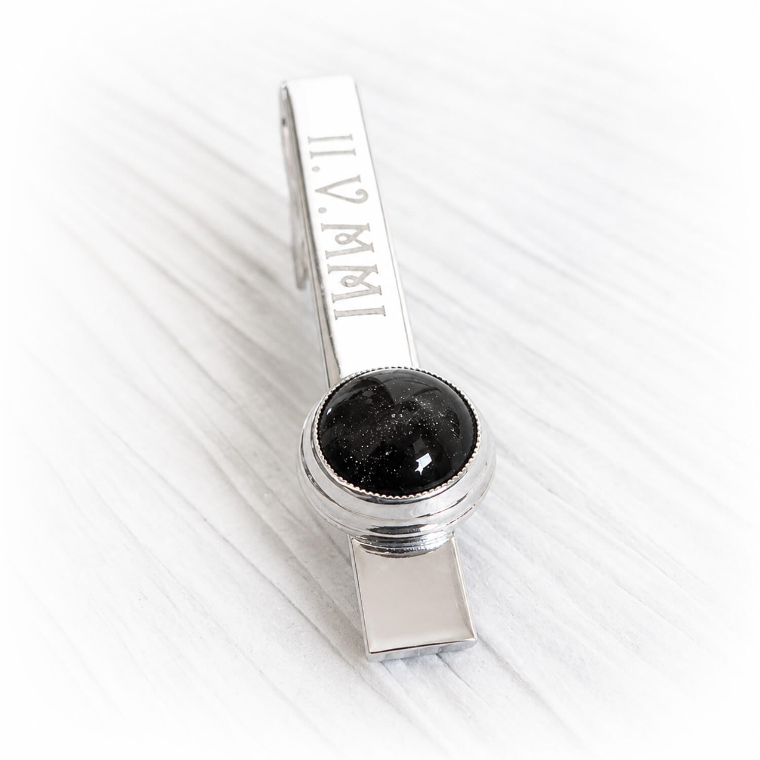 Sterling silver tie bar with personalized engraving featuring cremation ashes encased in a hand blown glass cabochon 