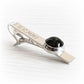 Commemorative tie bar displaying a flamework cabochon with cremation ashes sealed within glass set in sterling silver
