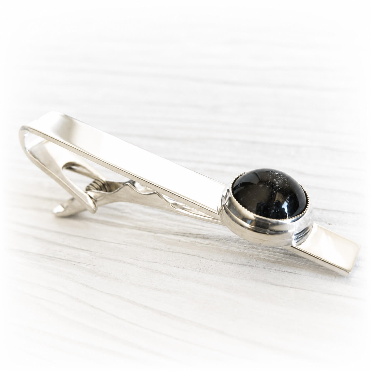 Hand blown glass memorial stone with cremation ashes set onto a sterling silver remembrance tie bar