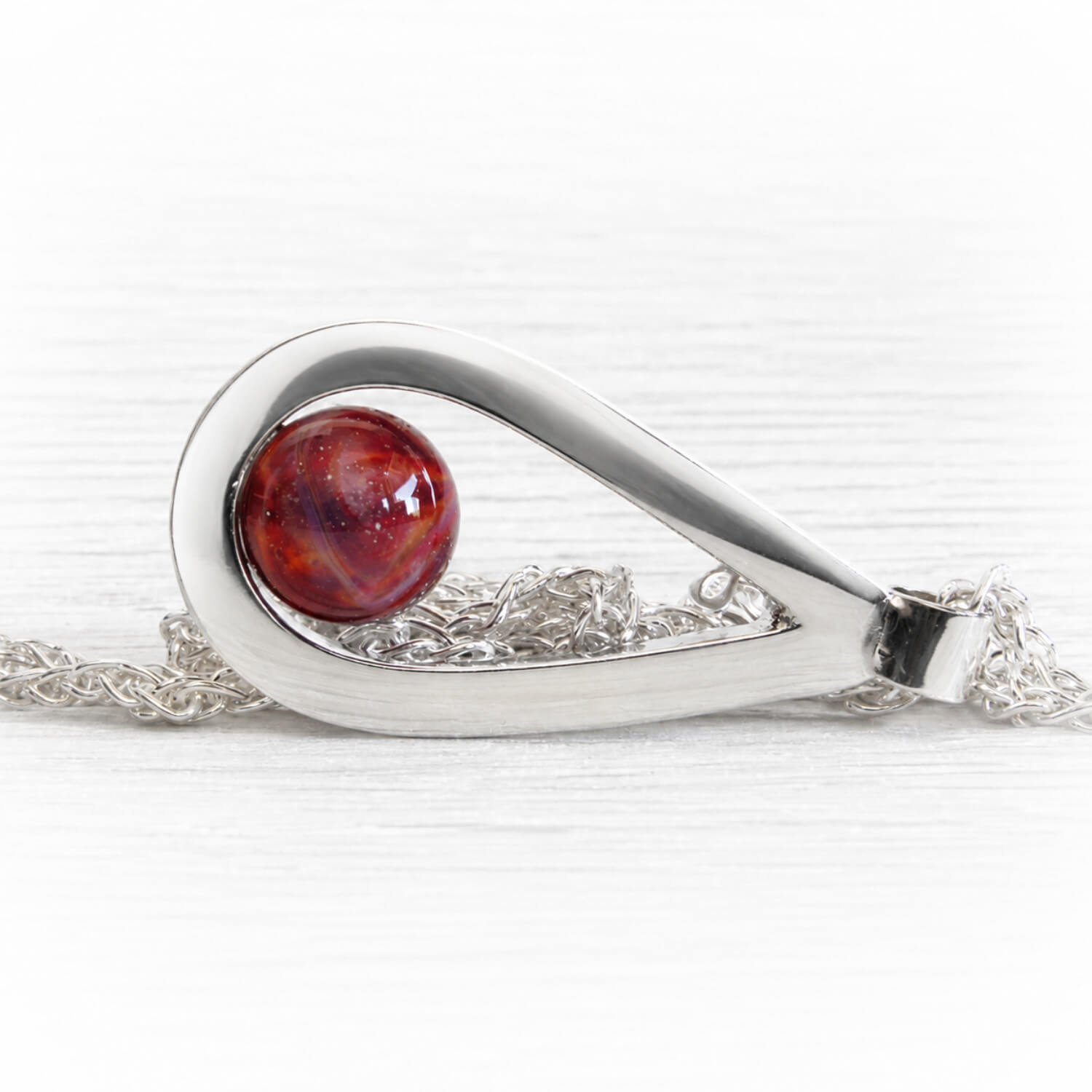 Hand forged polished sterling silver tear drop pendant featuring red glass swirled with cremation ashes