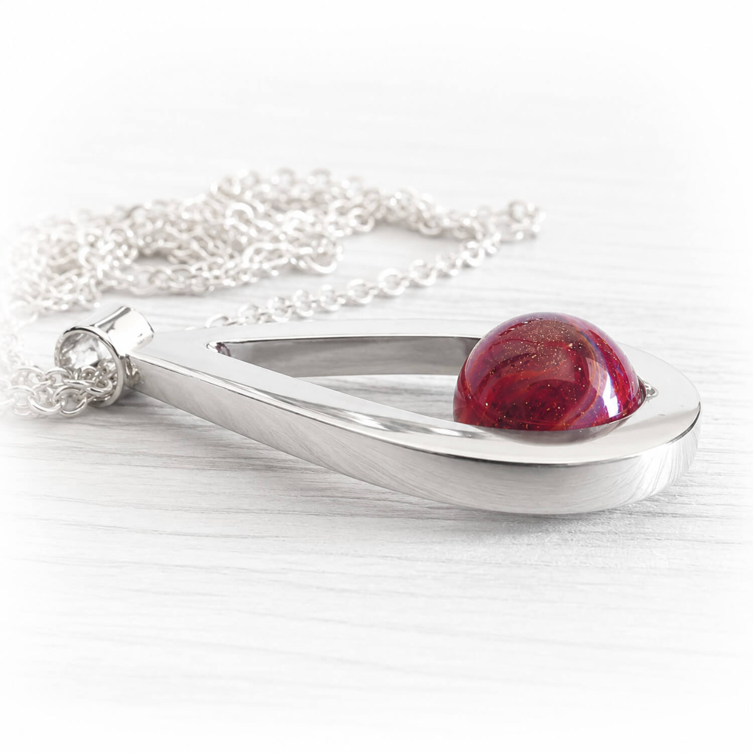 Deep red hand blown glass infused with cremation ashes set on a solid sterling silver memorial pendant