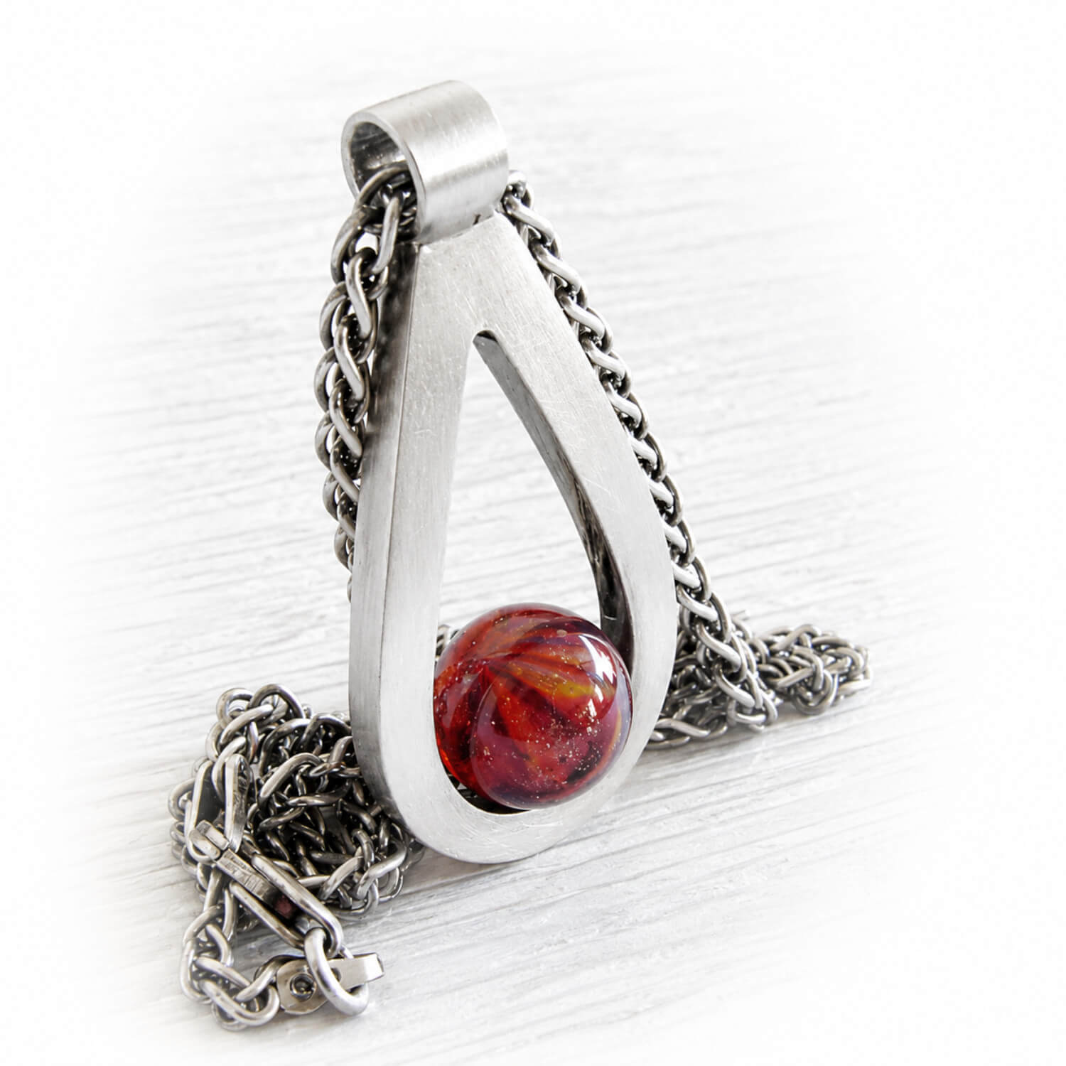 Colorful hand blown glass marble with ashes permanently encased in glass set in a sterling silver memorial pendant