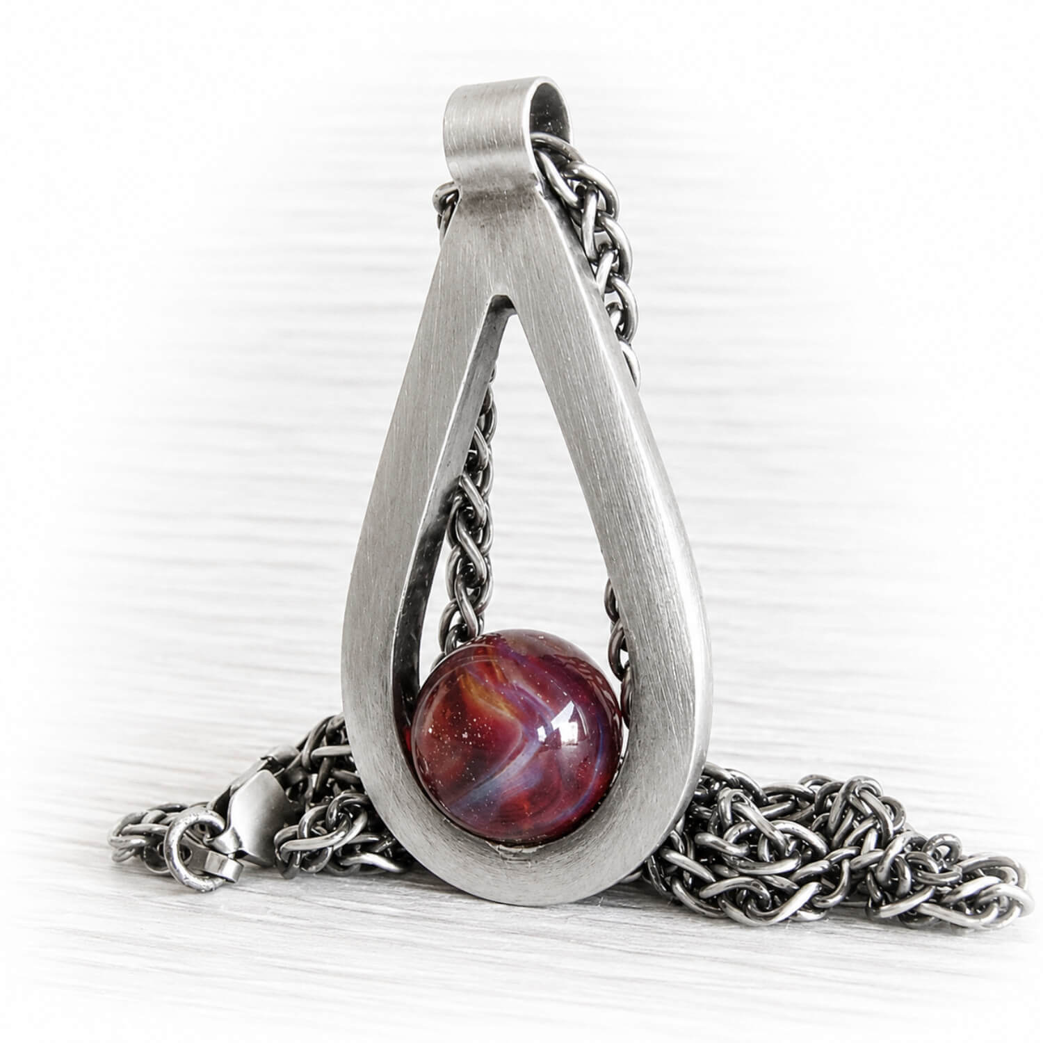 Sterling silver cremation pendant featuring a hand blown glass marble with swirls of red glass and pet ashes