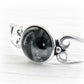 White cremation ashes swirled with black hand blown glass centered in a sterling silver memorial cuff bracelet