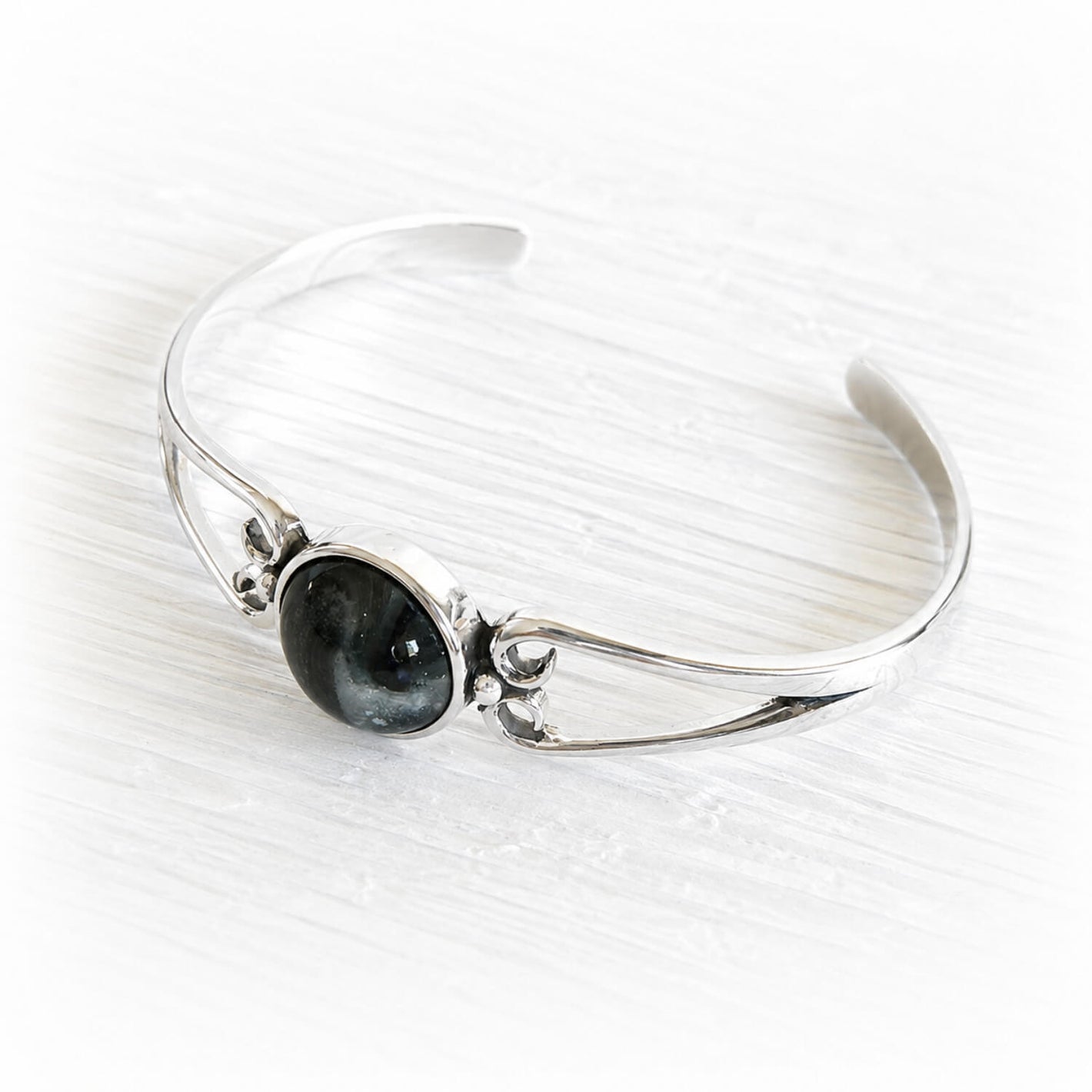 Polished sterling silver cuff bracelet with a centered hand blown glass cremation gem infused with pet ashes