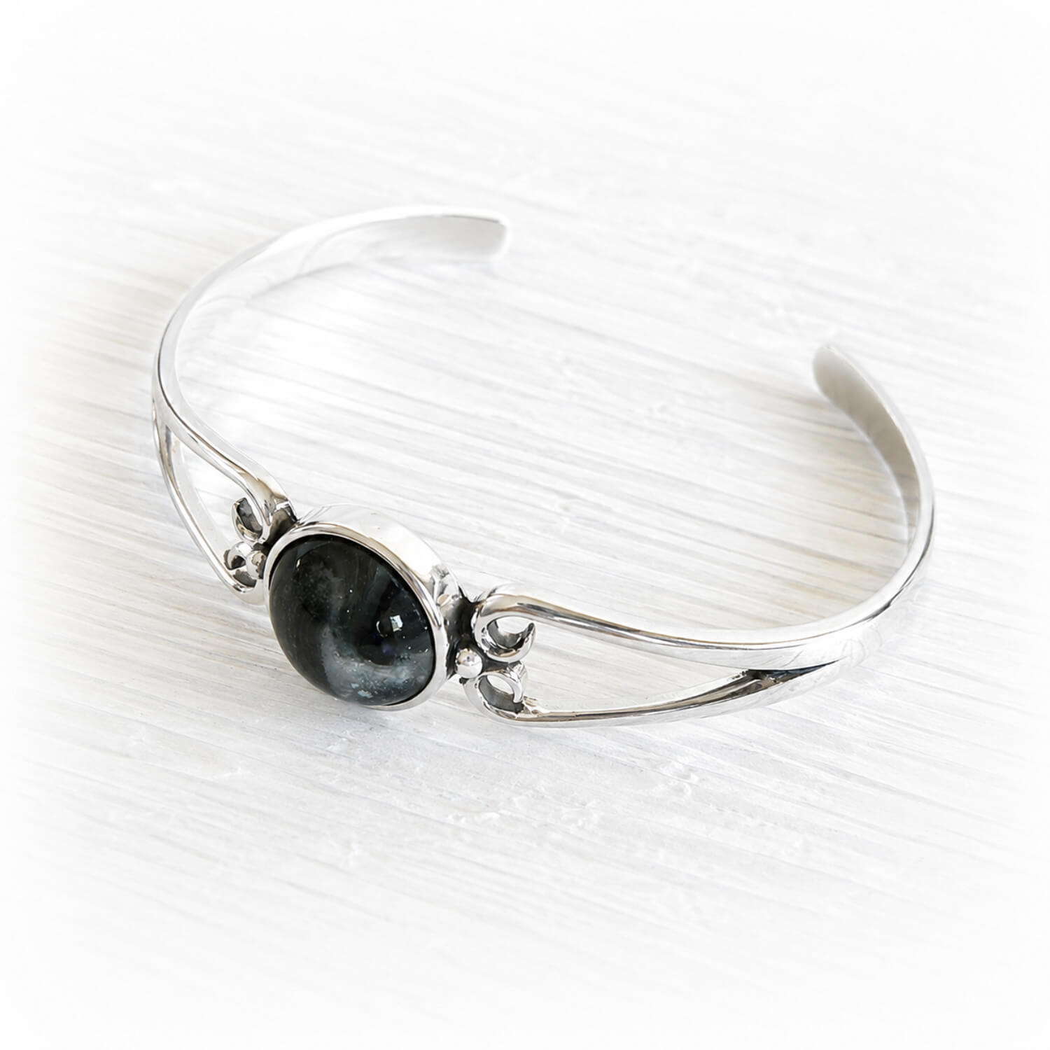 Polished sterling silver cuff bracelet with a centered hand blown glass cremation gem infused with pet ashes