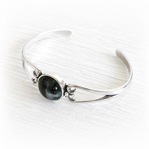 Polished sterling silver cuff bracelet with a centered hand blown glass cremation gem infused with pet ashes