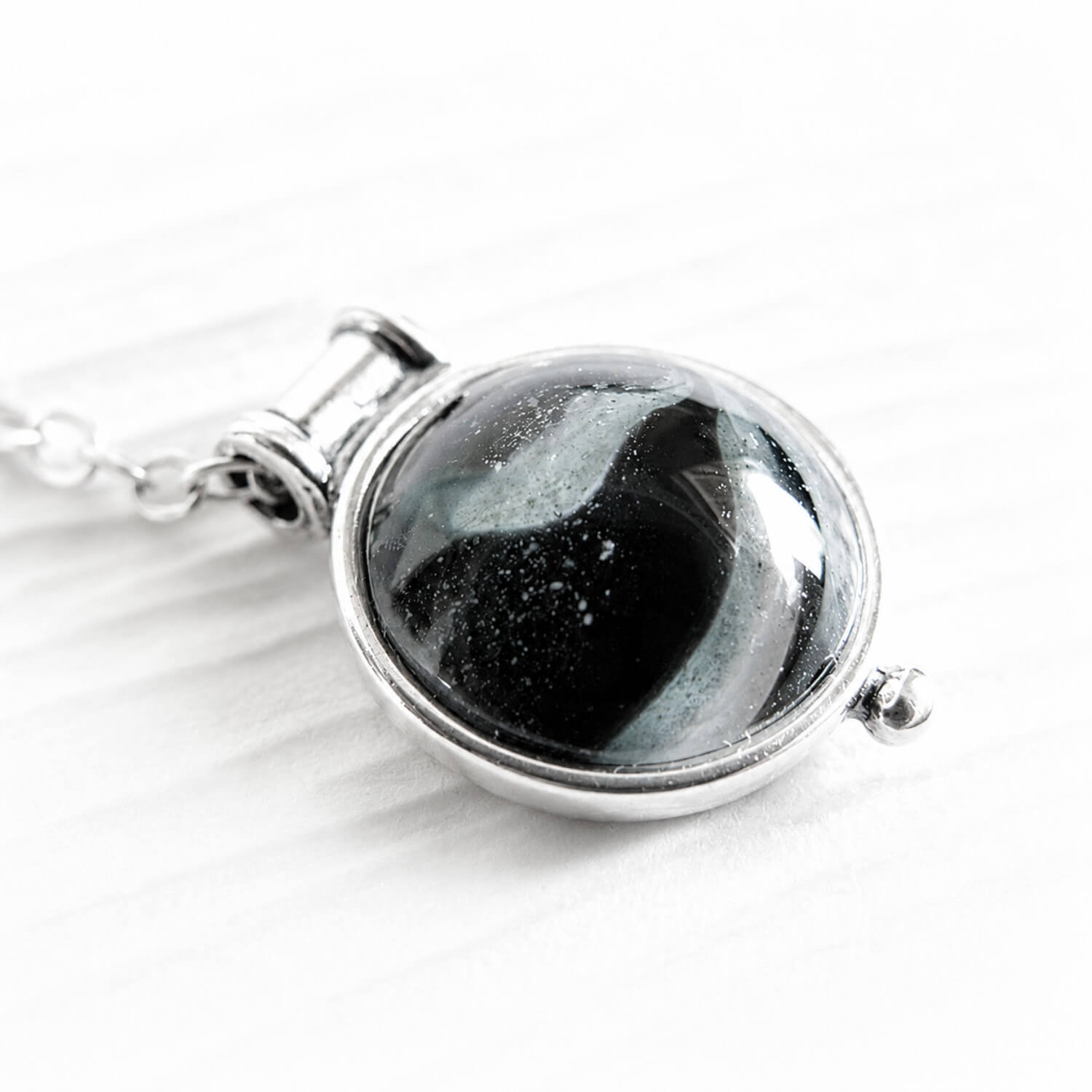 Pet ashes swirled with handcrafted memorial glass on a tiny sterling silver pendant