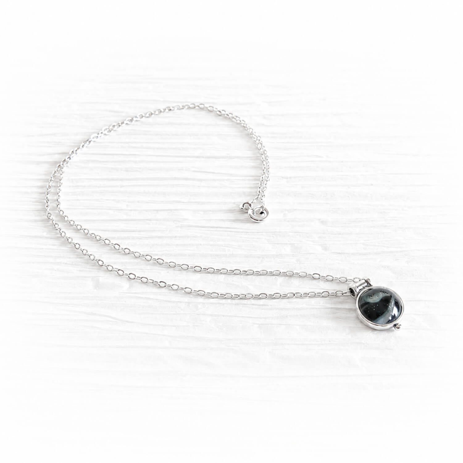 Tiny sterling silver memorial pendant with a handcrafted glass centerpiece encasing cremation ashes