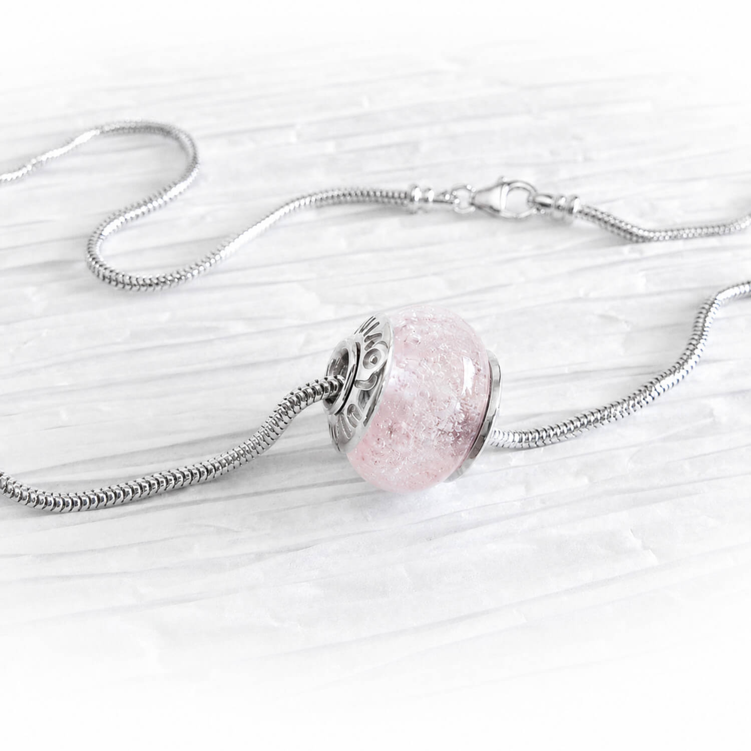 Silver memorial bead necklace with a pink glass pendant on a white background