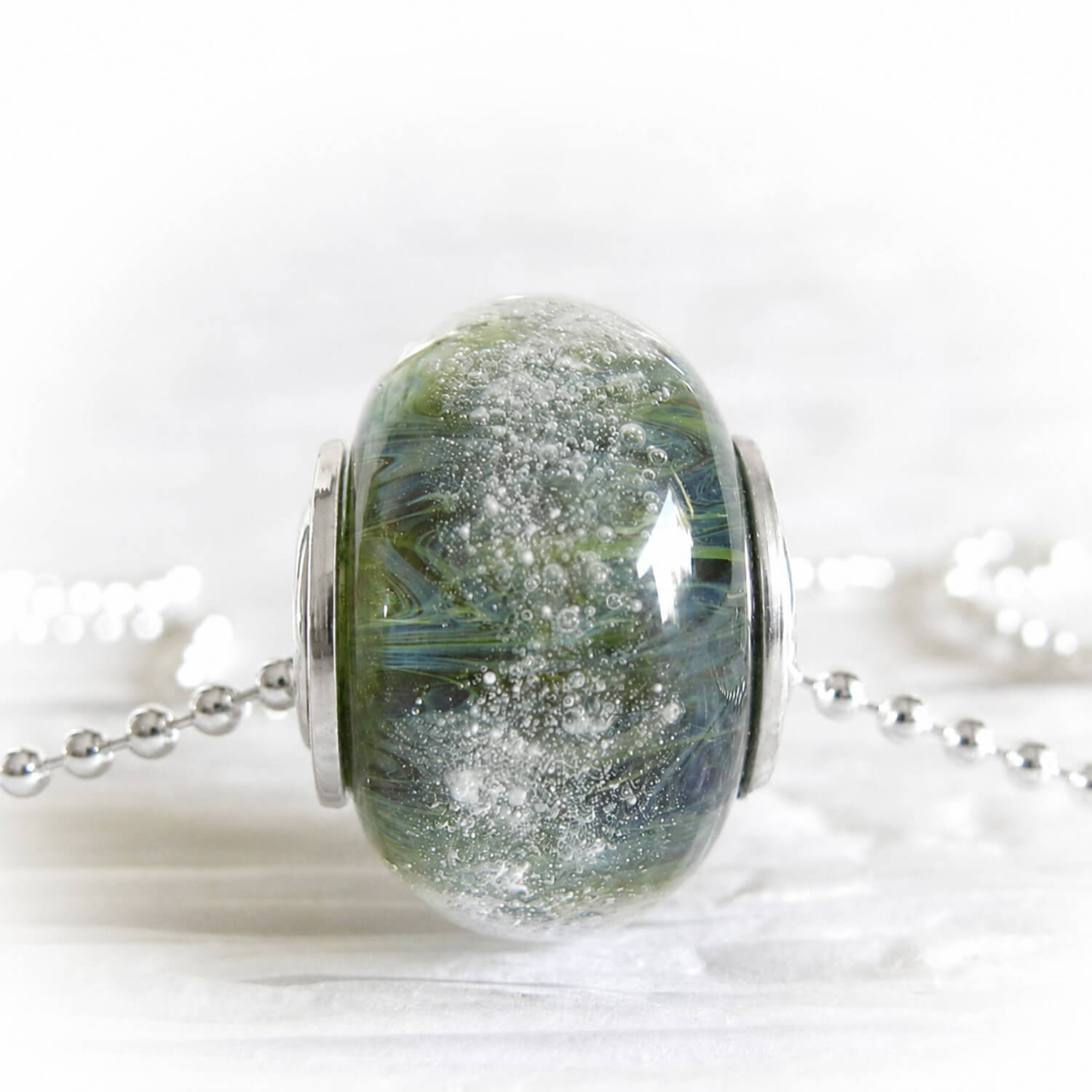 Hand crafted glass remembrance bead with ashes permanently encased in glass