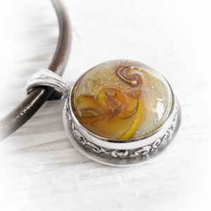 Amber and yellow hand blown glass swirled with cremation ashes set into a sterling silver pendant 