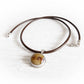 Pet memorial necklace with a circular glass cremation gemstone set in sterling silver in a brown leather chord