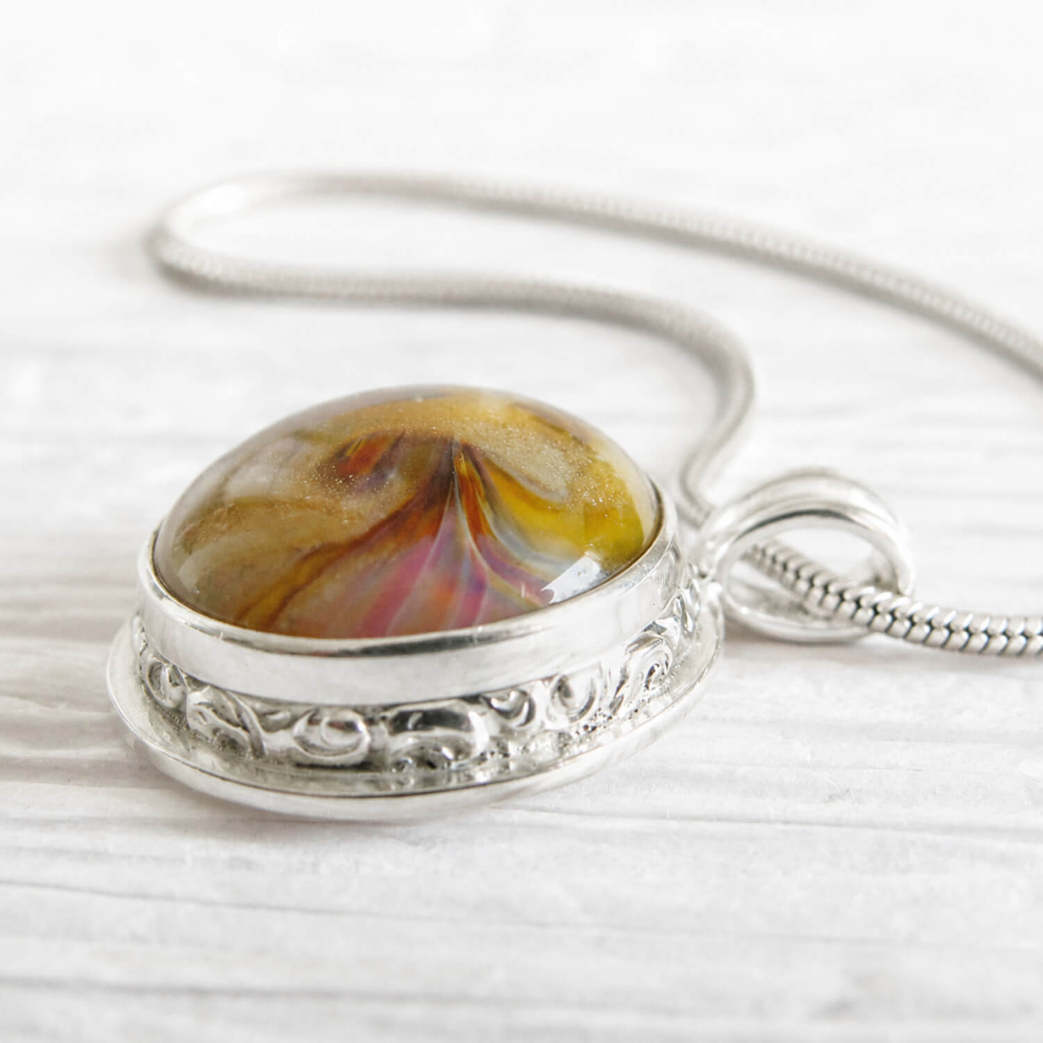 Yellow and amber glass swirled with pet cremation ashes set into a handmade sterling silver pendant 