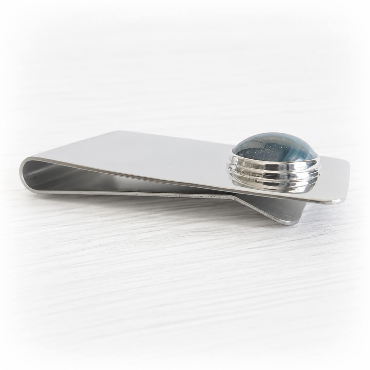 Sterling silver money clip including a hand blown glass cabochon with cremation ashes sealed within the glass