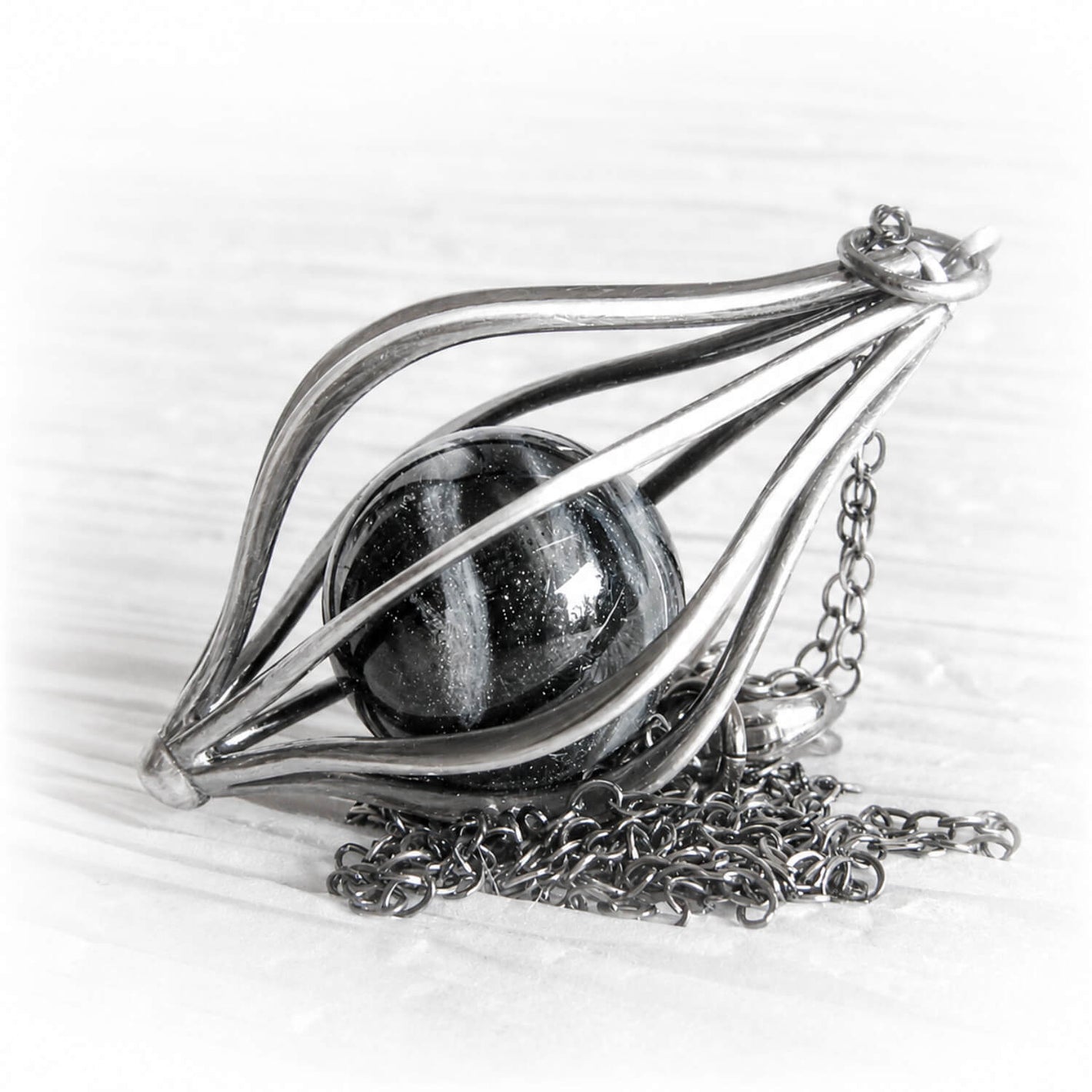 Hand blown glass pet memorial marble in a sterling silver pendant with an antique finish