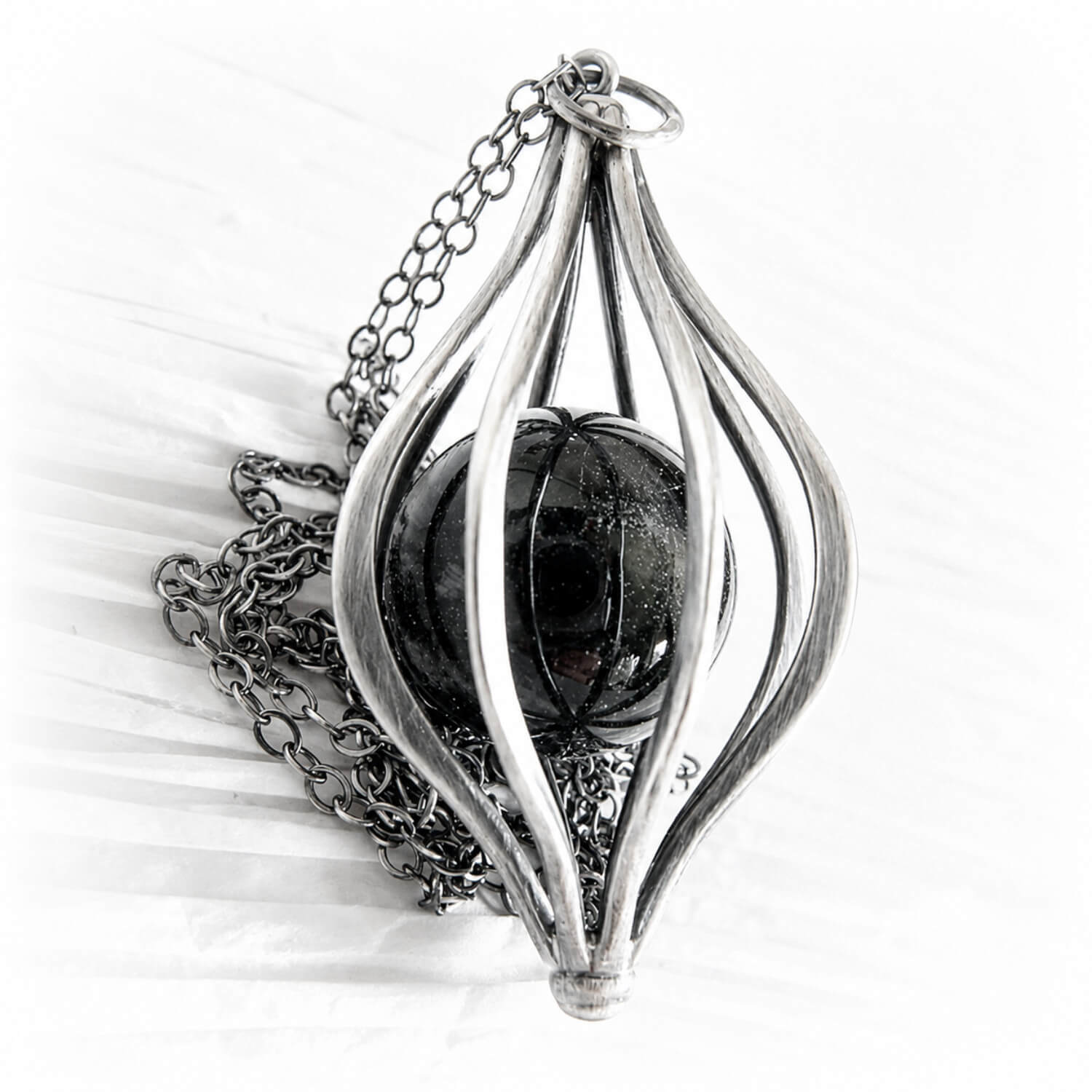 Sterling silver pet memorial with an antique finish displaying ashes encased in a handmade glass marble 