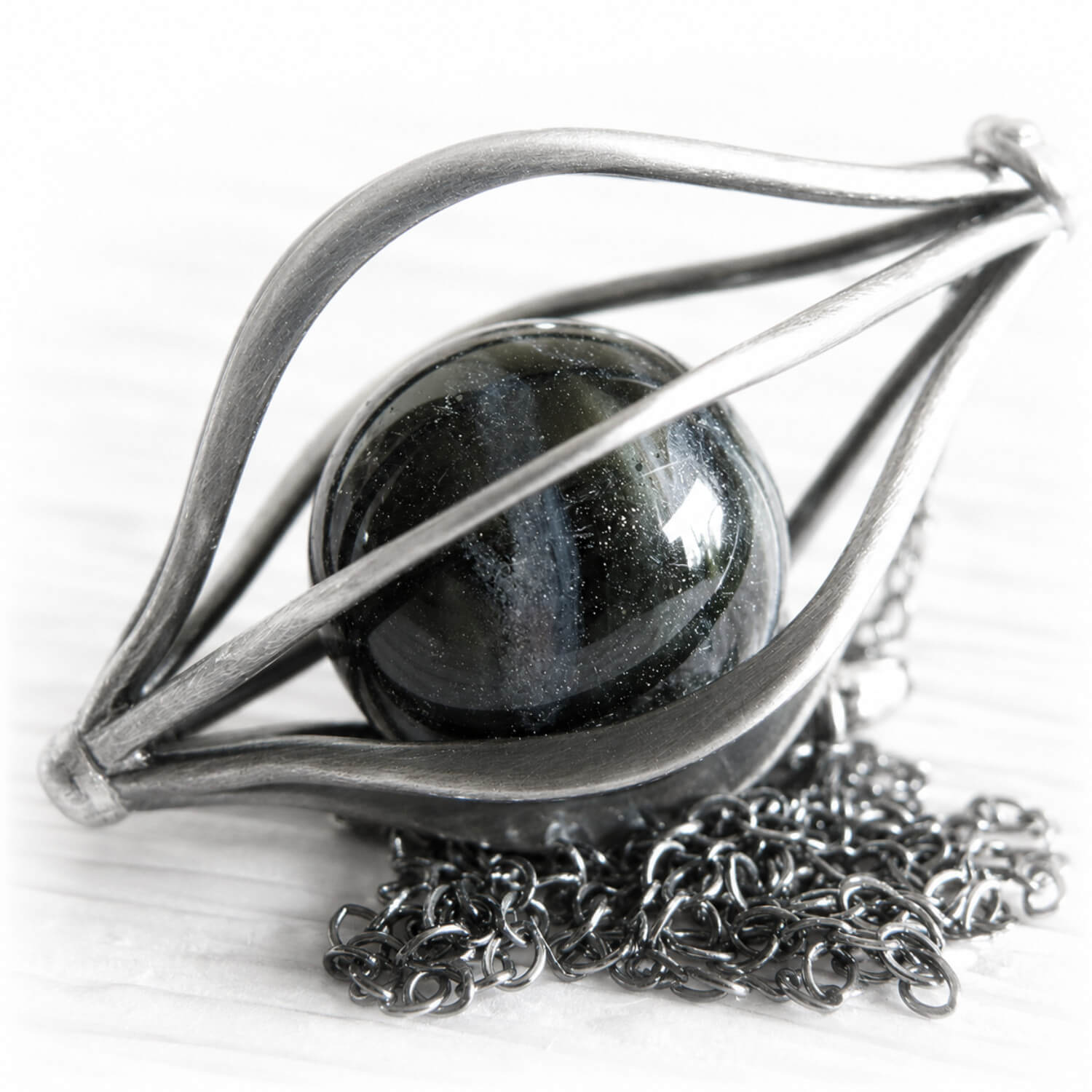 Sterling silver cage pendant incorporating a central black glass marble with ashes permanently encased in glass