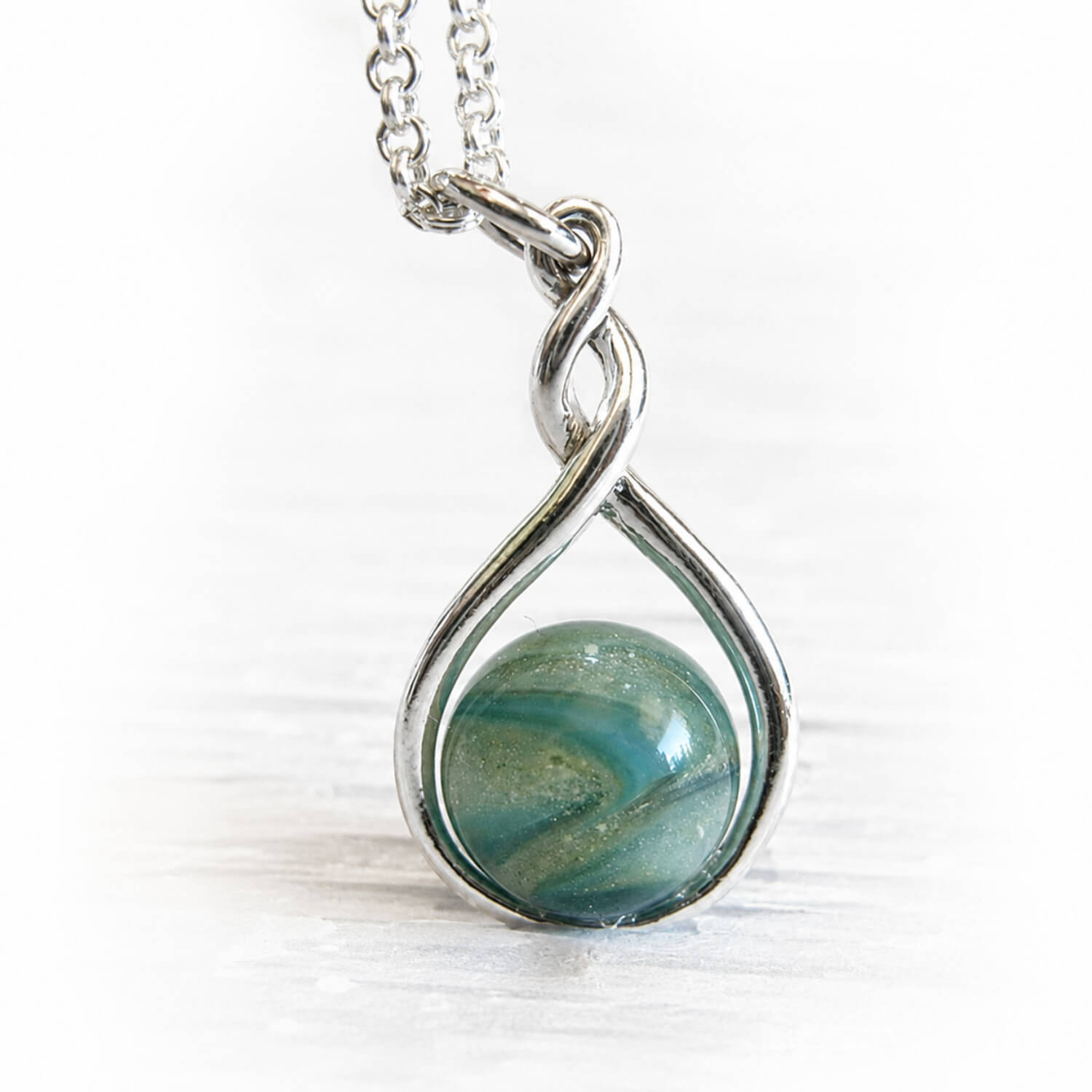 Teardrop shaped pendant with a flamework aqua and turquoise glass memorial marble infused with cremation ashes 