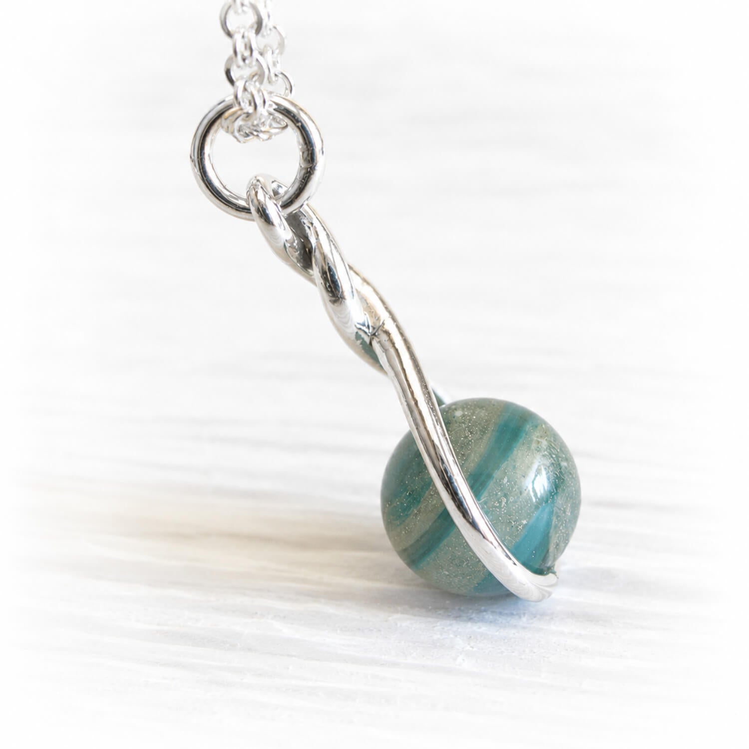 Handcrafted memorial glass marble with ashes swirled within turquoise and aqua glass set on a sterling silver pendant